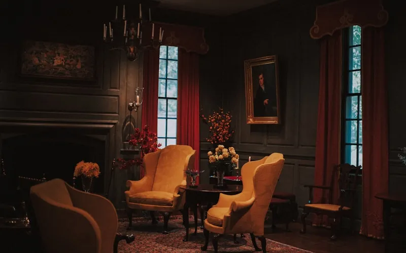 Traditional classic furniture arrangement with wingback chair beside a fireplace