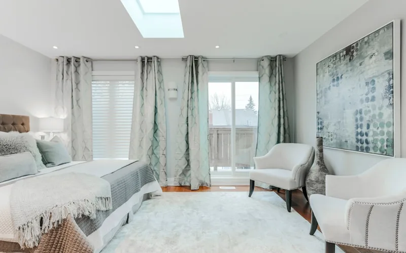 Living room showing ideal curtain rod placement high near ceiling with panels extending past window frame