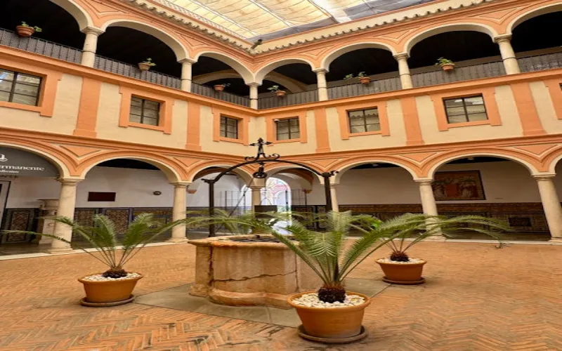 Hacienda-style interior with arched doorways, exposed wooden beams, and terracotta tile floors