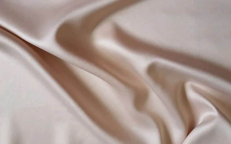 Luxurious textiles including velvet cushions and silk curtains in neutral tones