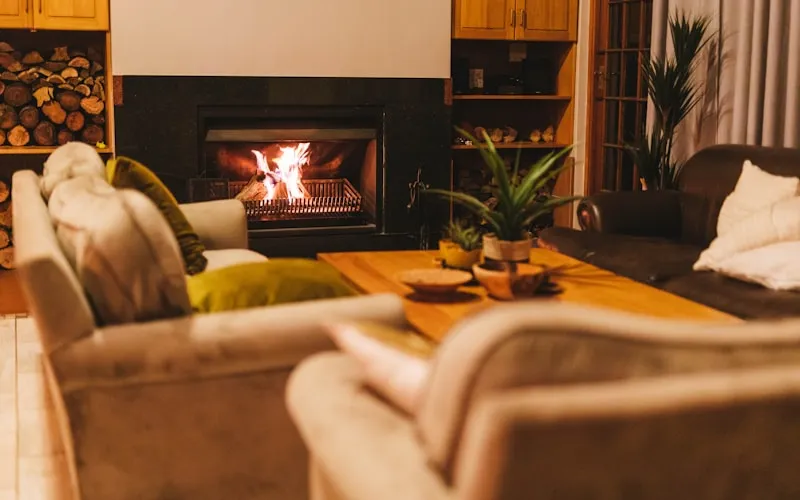 Warm and cozy living room with fireplace, soft blankets, and earthy color palette